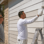 American homeowner painting sunlit siding to show cool paint benefits for hot weather homes in summer heat